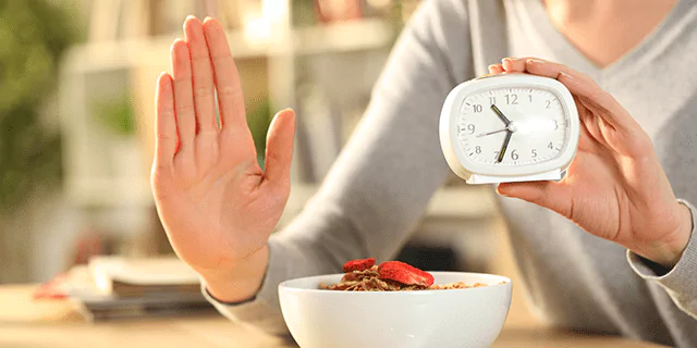 a person showing a stop sign with one hand and holding a clock with another hand