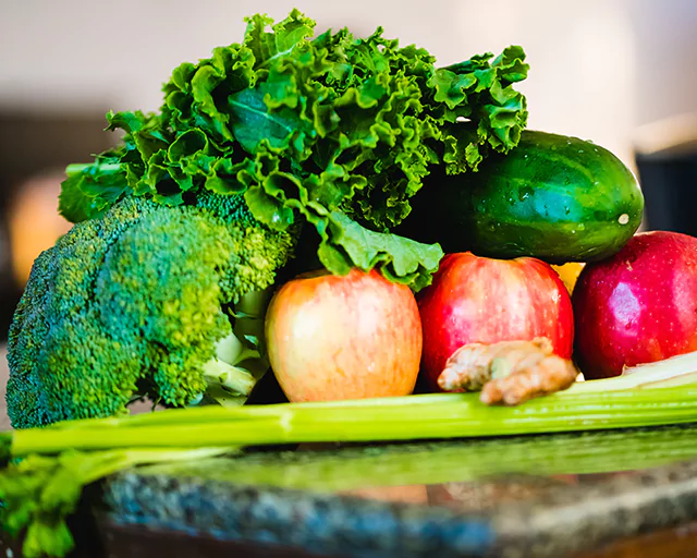 a broccoli, a cucumber, green leafy vegetables and apples