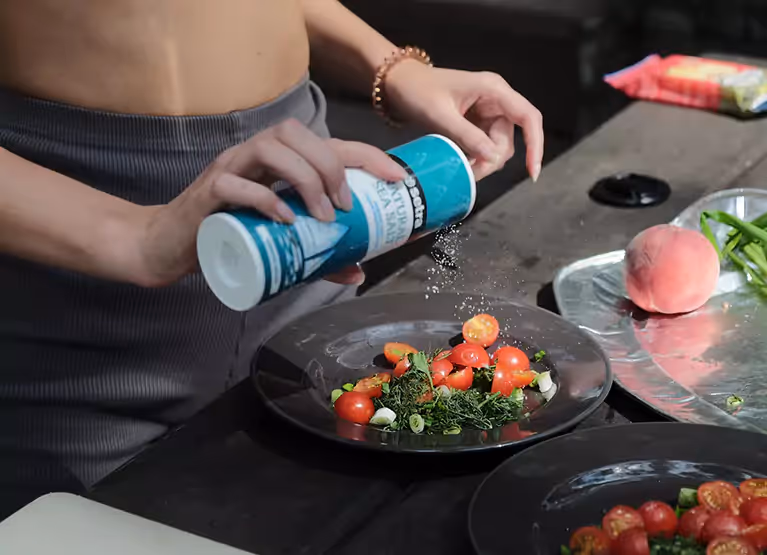 putting salt on a plate of vegetables