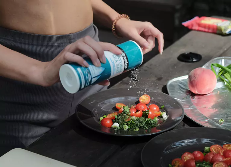 putting salt on a plate of vegetables