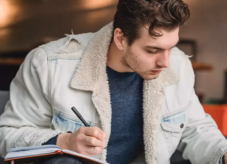 Person writing in their blood sugar log notebook