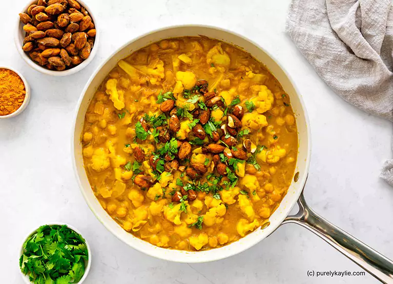 Bowl of turmeric curry with cauliflower, almonds, and cilantro