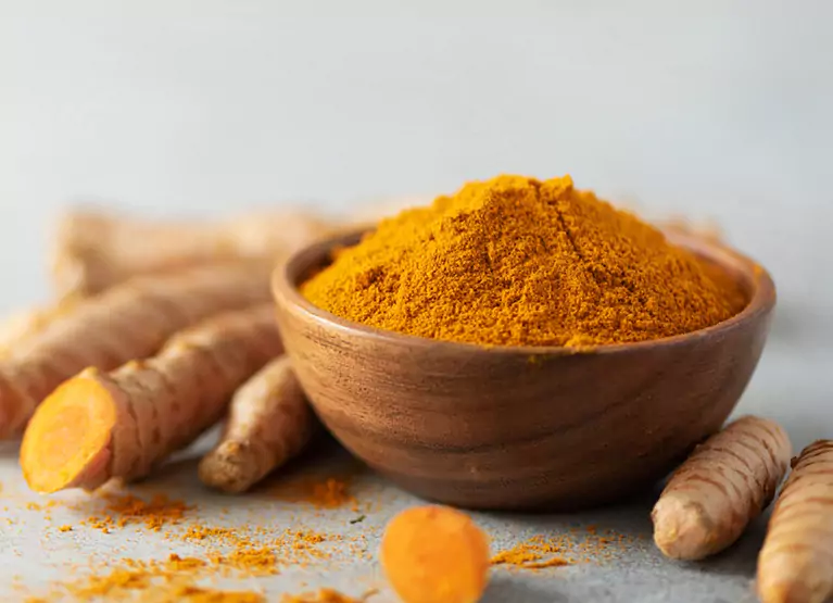 Wooden bowl with turmeric root powder