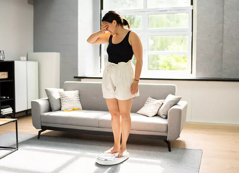 a woman who looks disappointed standing on a scale