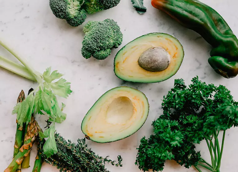 Close up of broccoli florets, asparagus, and avocado cut in half