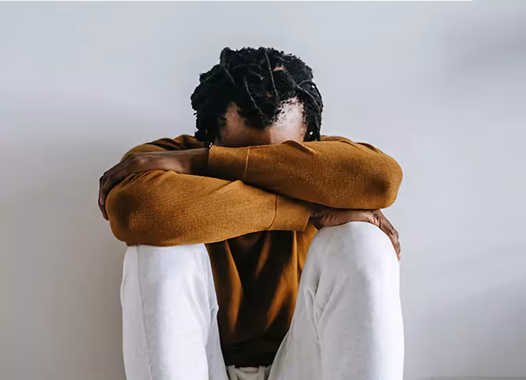 Person sitting on floor with knees drawn to chest