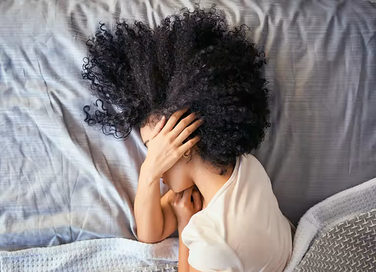 Woman holding her head and laying in bed