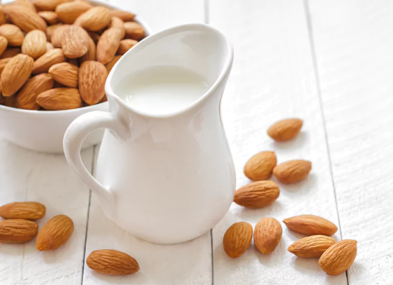 a bowl of almonds and glass of almond milk