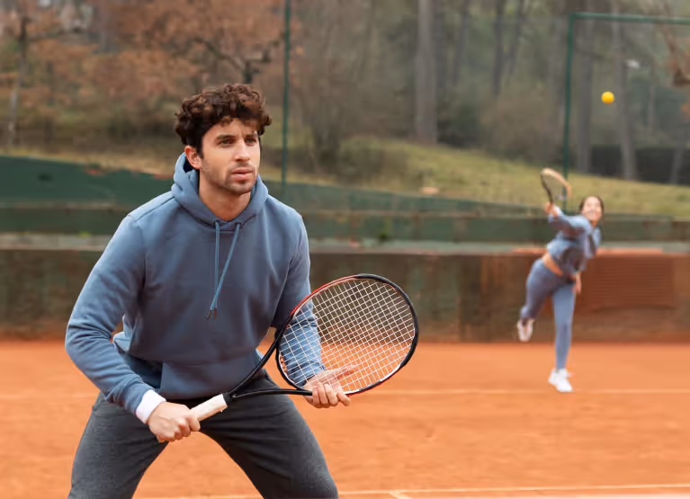 Man and woman playing tennis during fall season