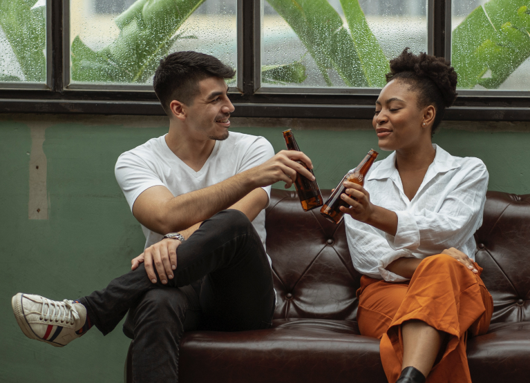 Man and woman clinking beer bottles together