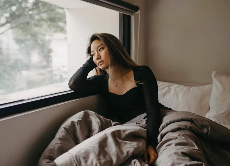 a girl in bed looking out the window