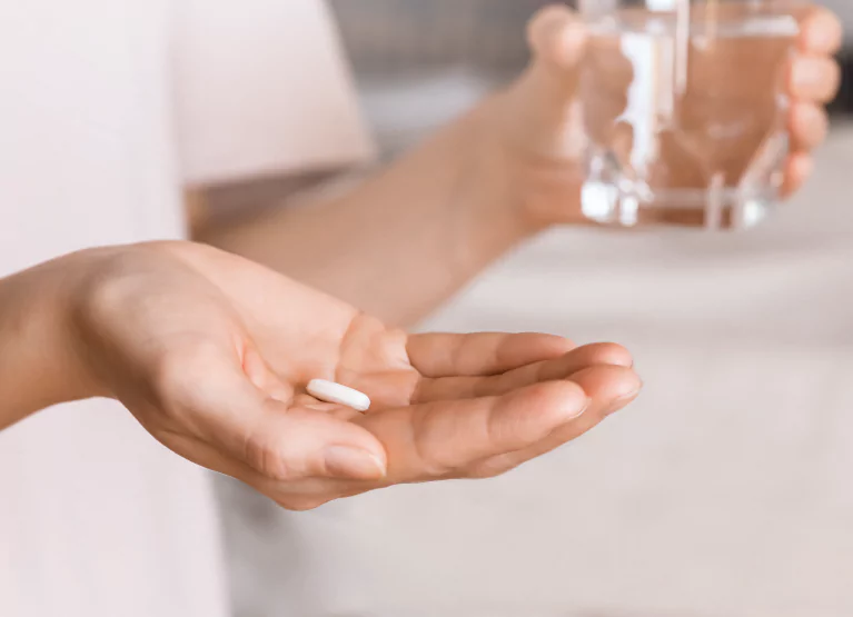 someone holding a pill and glass of water