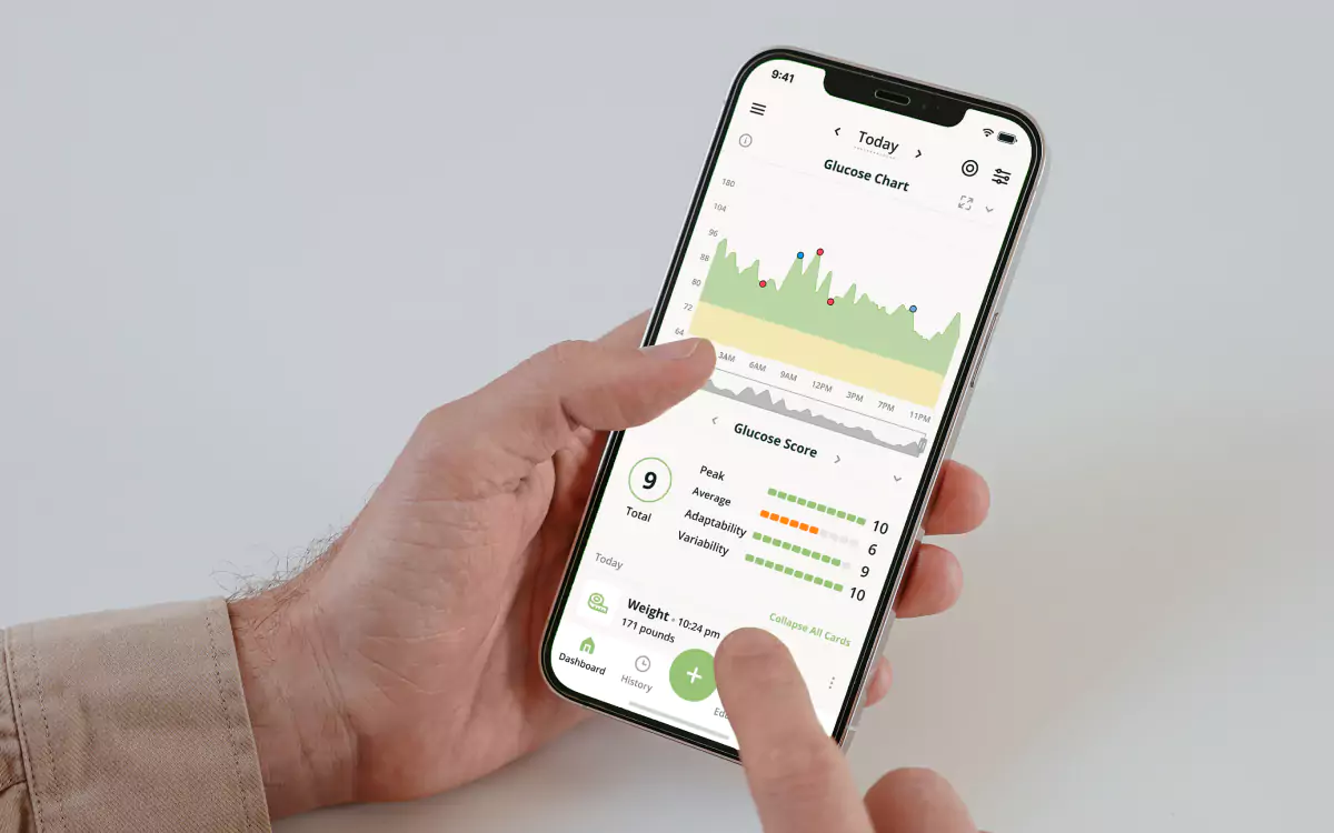 A closeup of a hand holding a mobile phone with the screen showing a blood glucose chart in the Nutrisense app