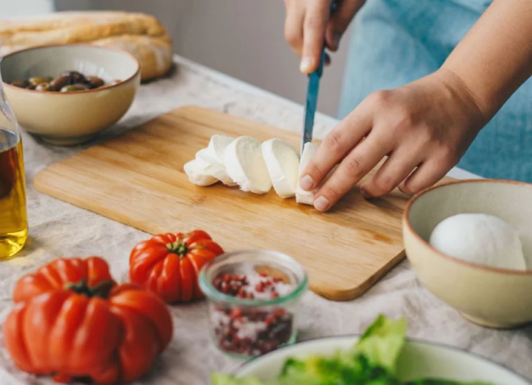 someone cutting cheese on a cutting board