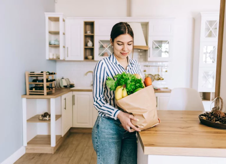 a woman opening a shopping bag full of fresh produce