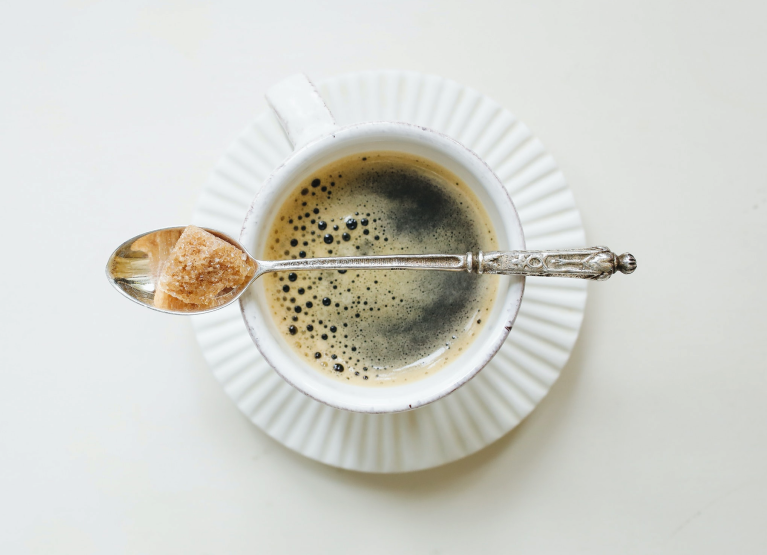 Cup of coffee with spoon on top that is holding a sugar cube