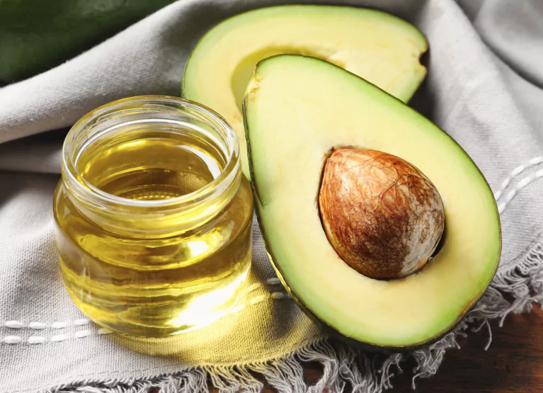 a sliced avocado and a jar of oil