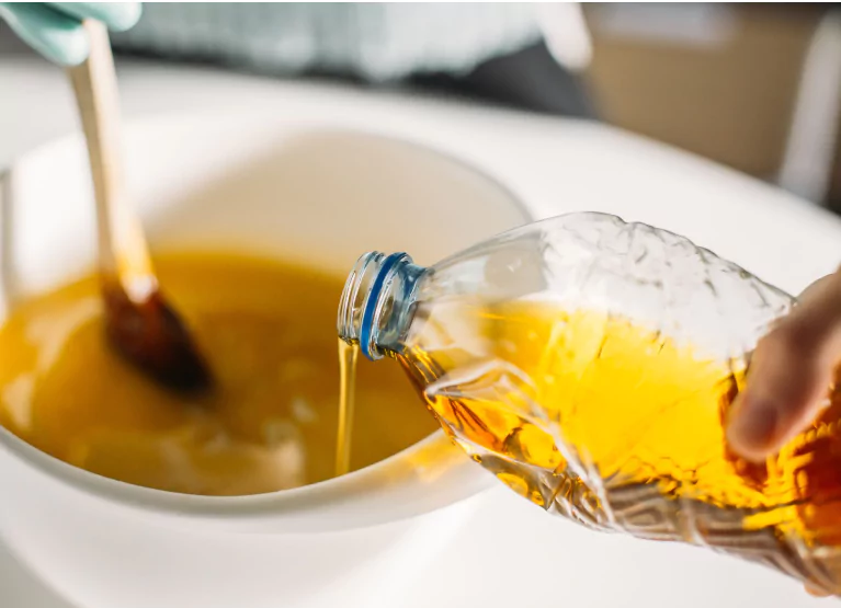 someone pouring canola oil into a bowl