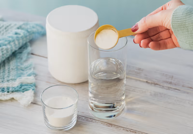 Person putting collagen powder into glass of water