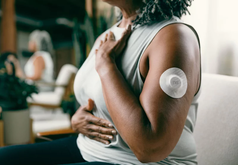 a woman sitting with a nutrisense patch