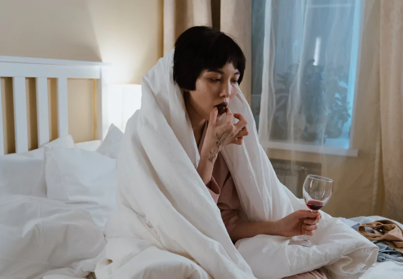 a girl in bed with a glass of wine