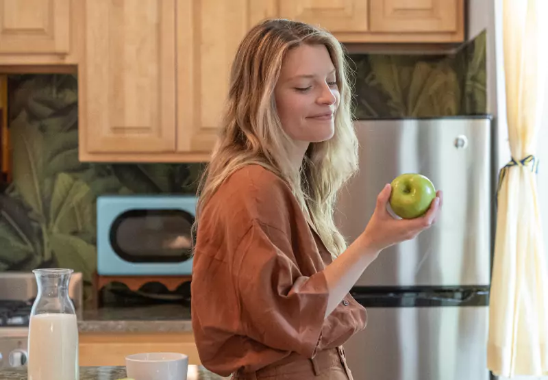 Woman holding an apple in her kitchen