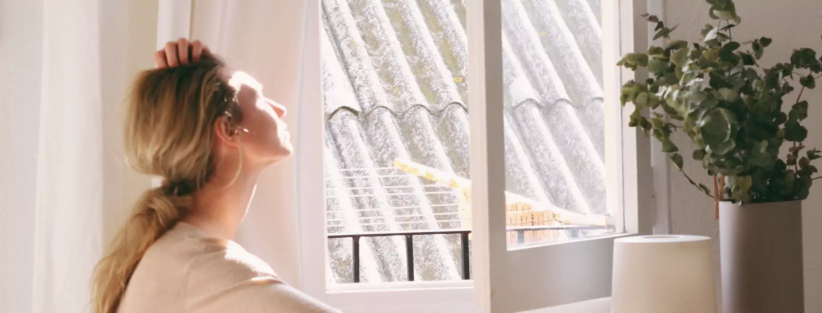 a person sitting near a window and looking at the sun