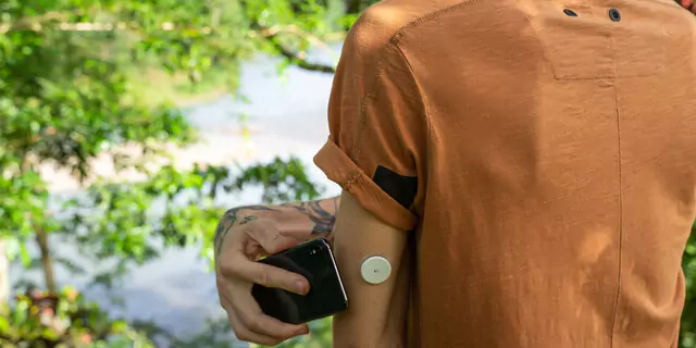 A person scanning a CGM sensor with a smartphone
