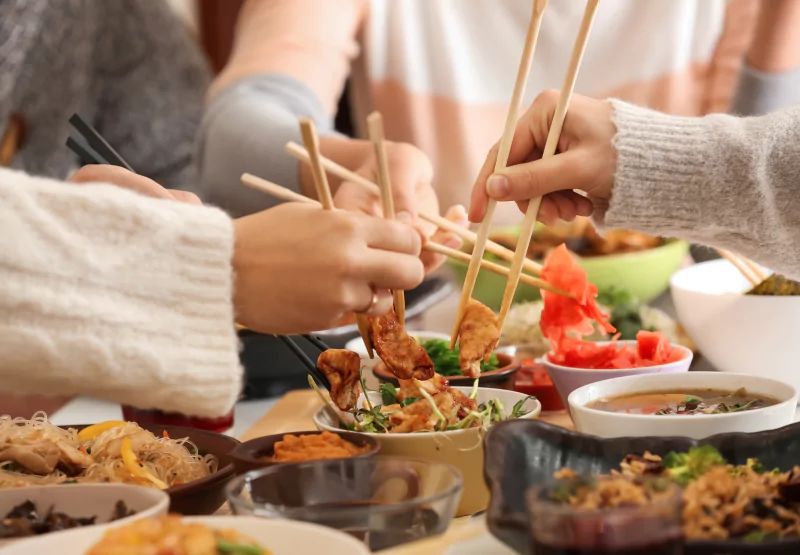 Group of friends eating Chinese takeout with chopsticks