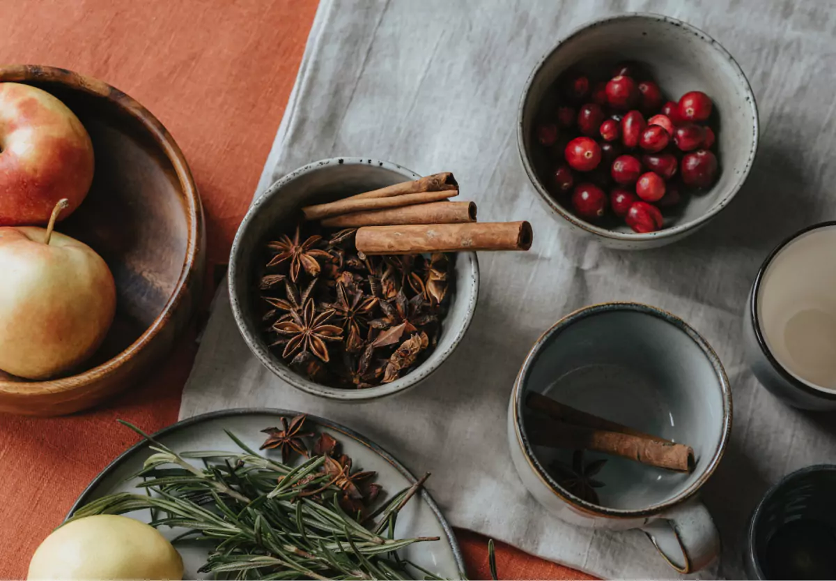 a bowl of cinnamon sticks, coves, and cranberries