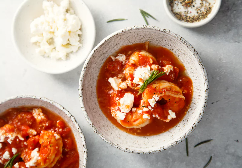 a plate of tomato sauce, shrimp, and rice