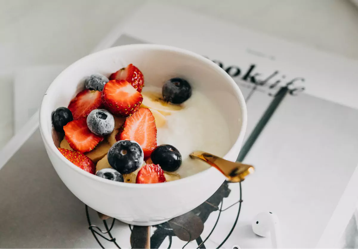 A white bowl filled with yogurt, strawberries and blueberries