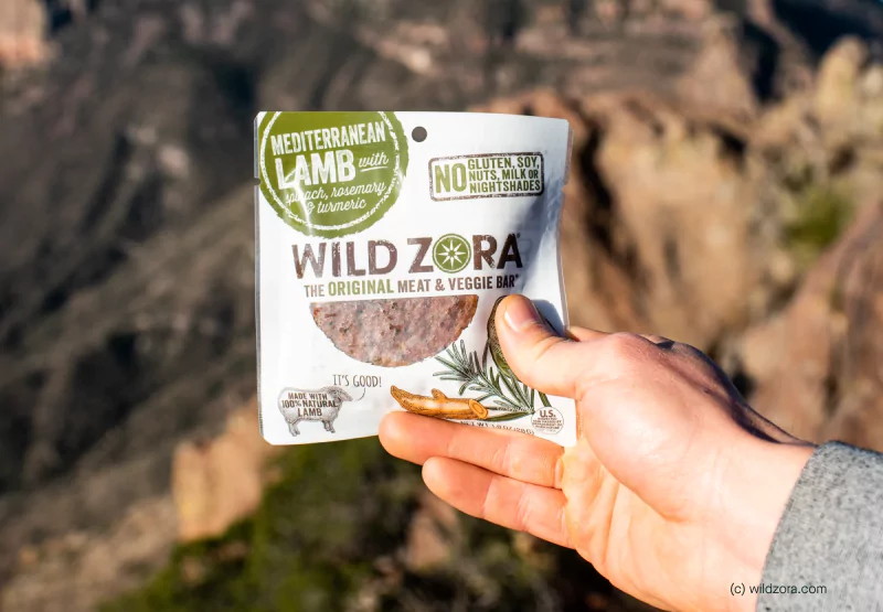 A closeup of hands holding a packet of Wild Zora meat and veggie bars