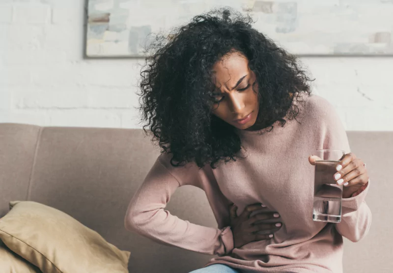 a girl holding her side and drinking water