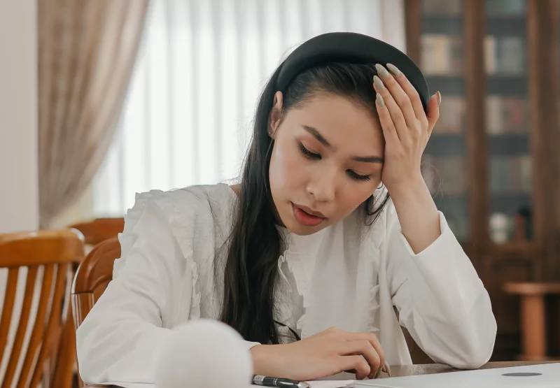 a girl holding her head while sitting down