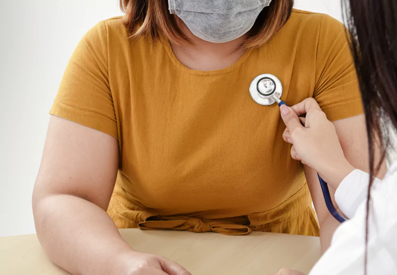 a heavy set person getting their heartbeat checked at the doctor