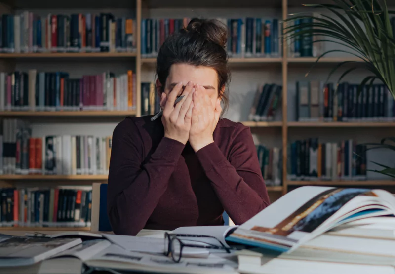 a girl with her hands covering her face while studying