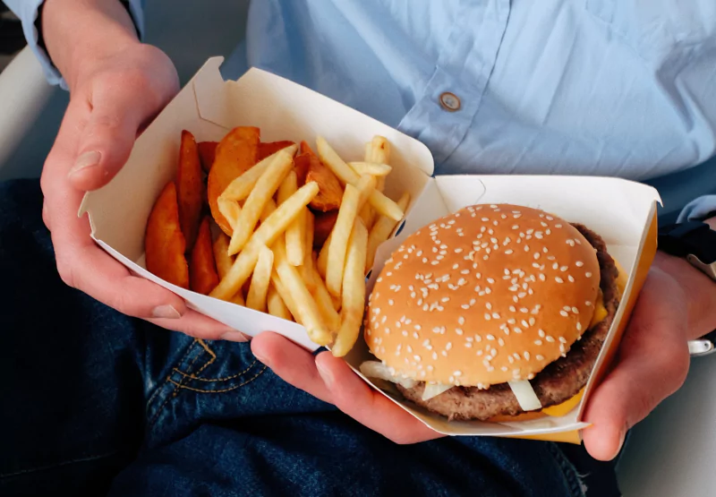 someone holding a fast food hamburger with fries