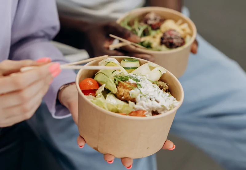 two people eating to-go salads