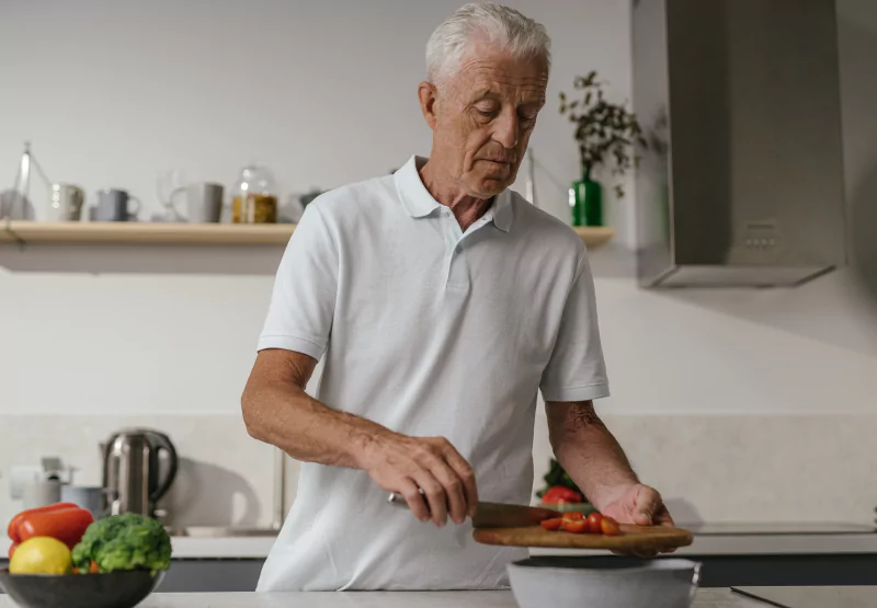 a man chopping tomatoes in the kitchen