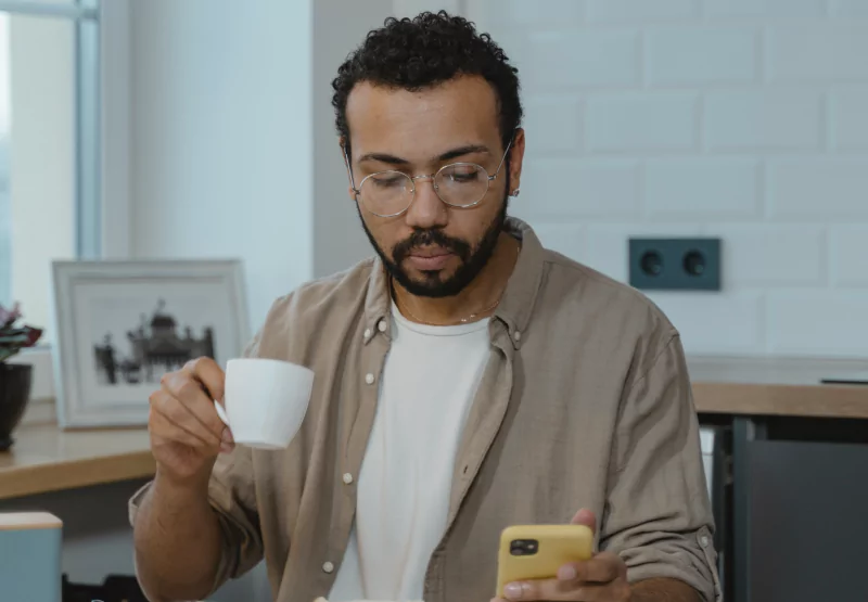 a man drinking a coffee and looking at his phone