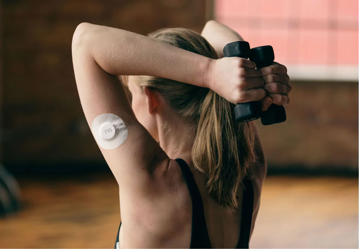 a woman lifting weights with a nutrisense cgm