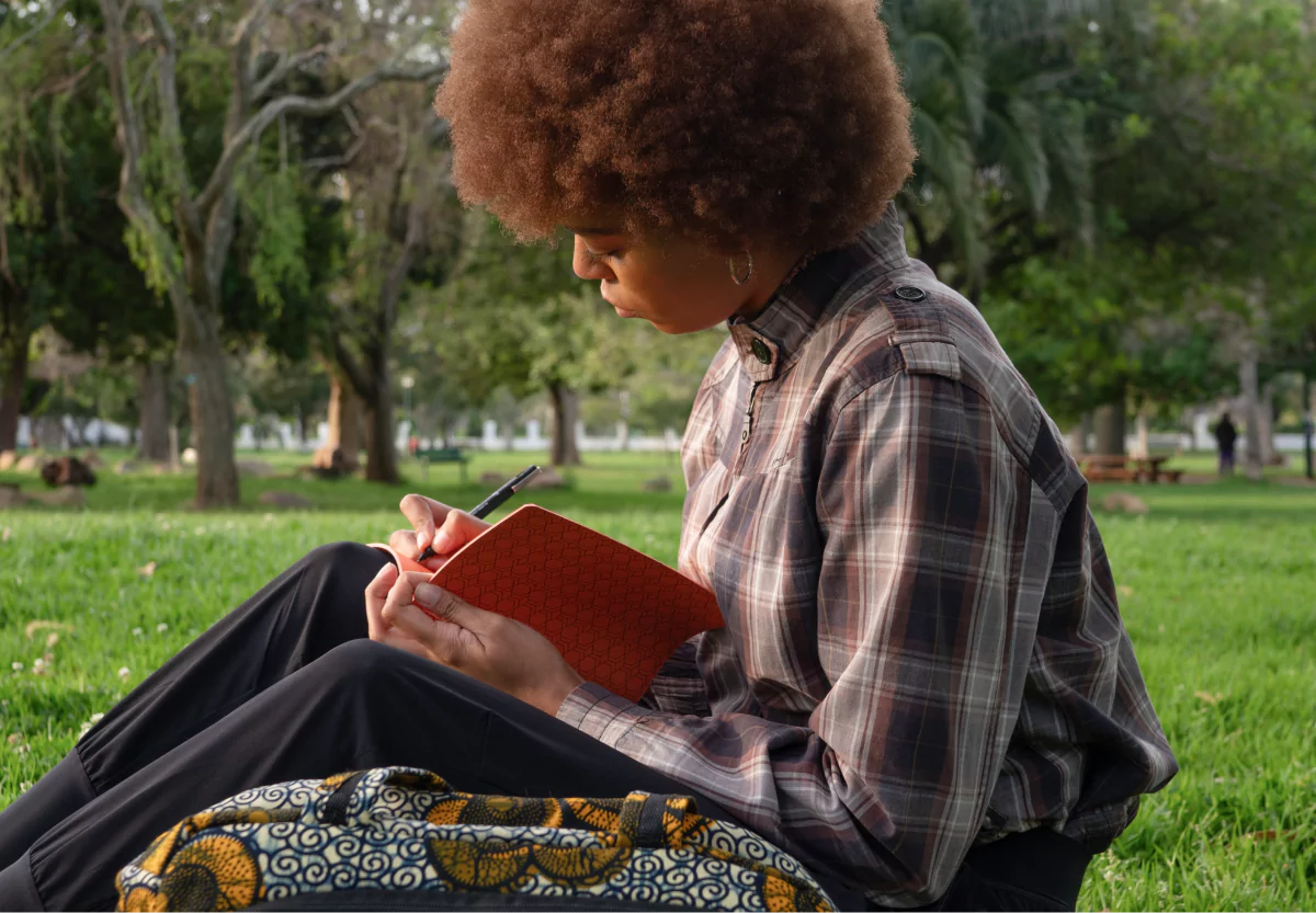 a woman writing in a journal in the park