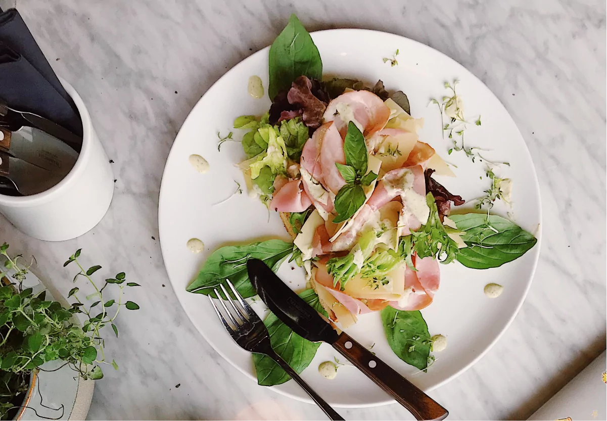 a plate of ham, cheese, and greens