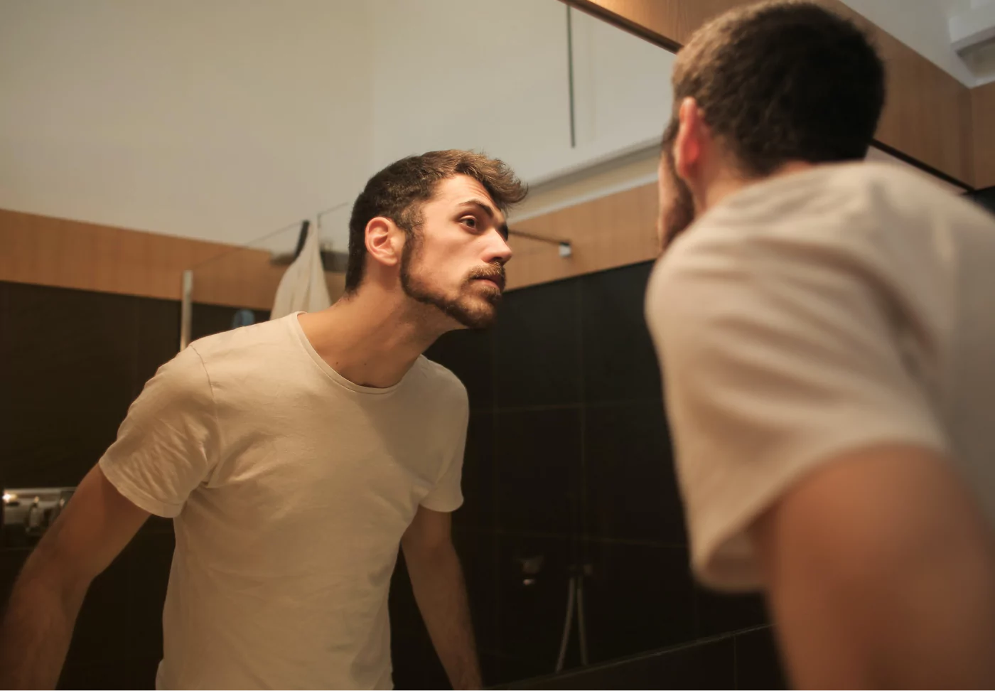 a man looking at his face in the mirror