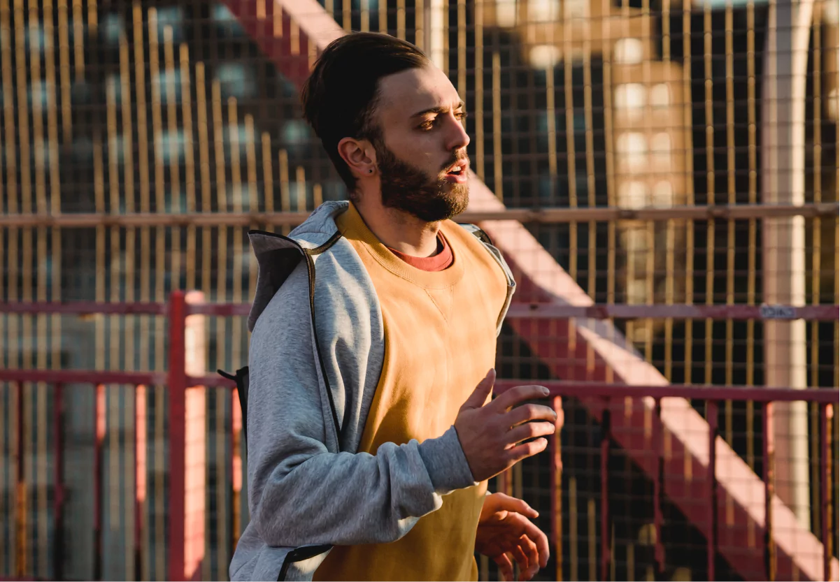 A man wearing a sweatshirt running outside