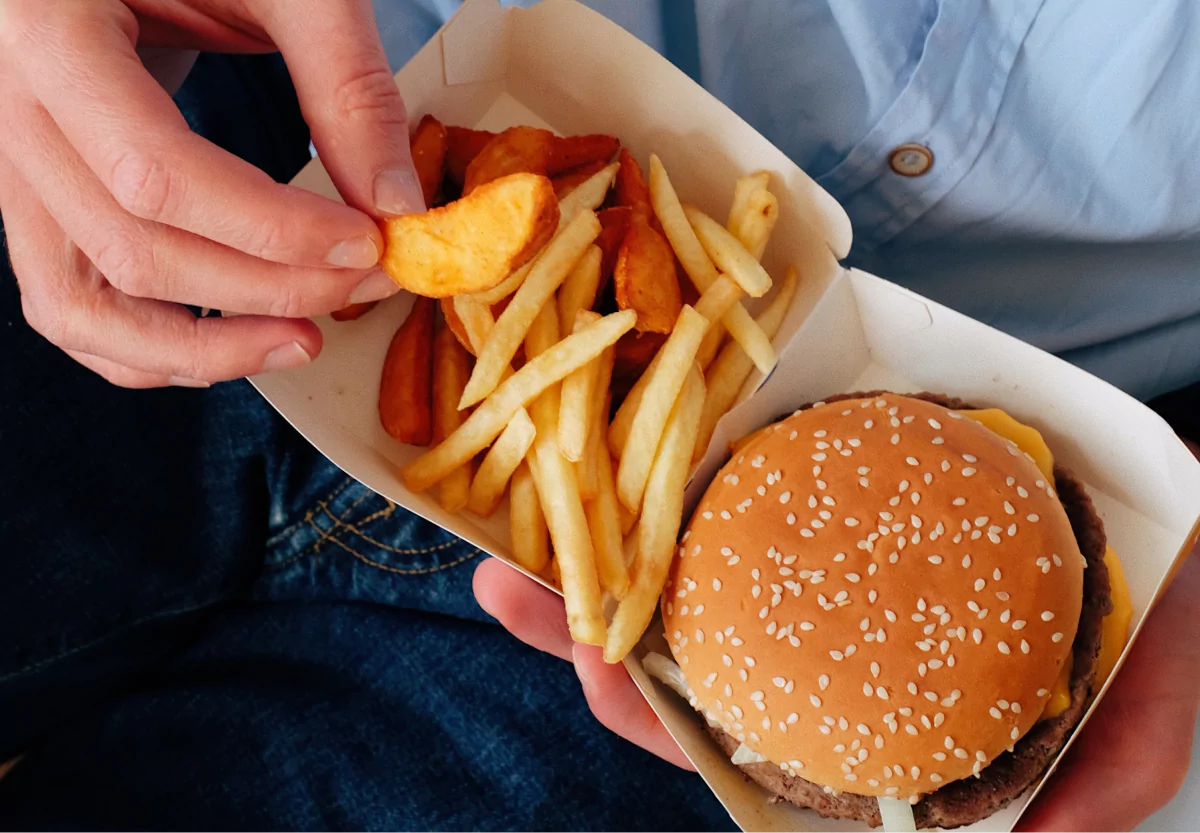 someone eating french fries and a burger