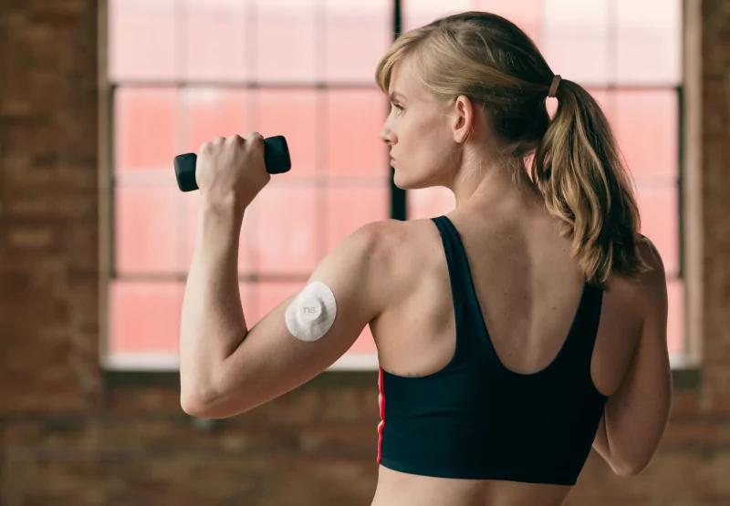 a girl with a nutrisense patch doing a dumbbell workout