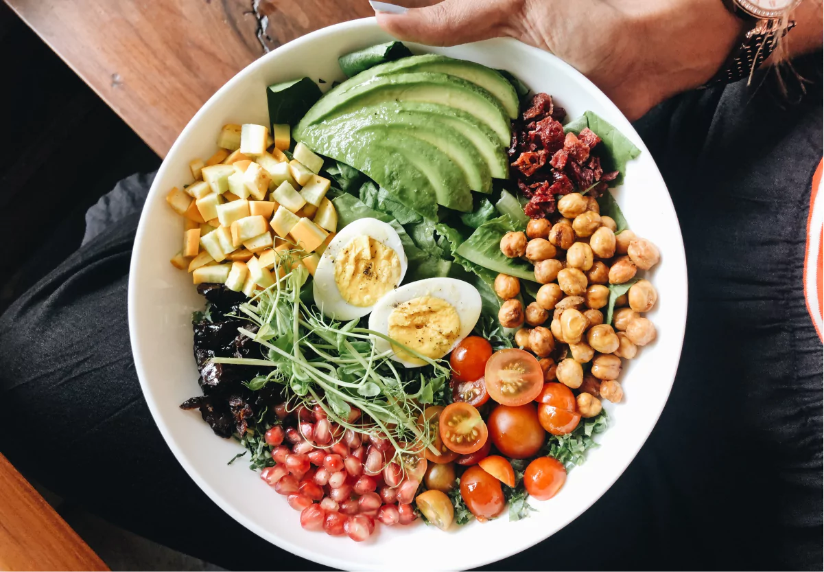 a salad bowl with eggs, tomatoes, avocado, and chickpeas