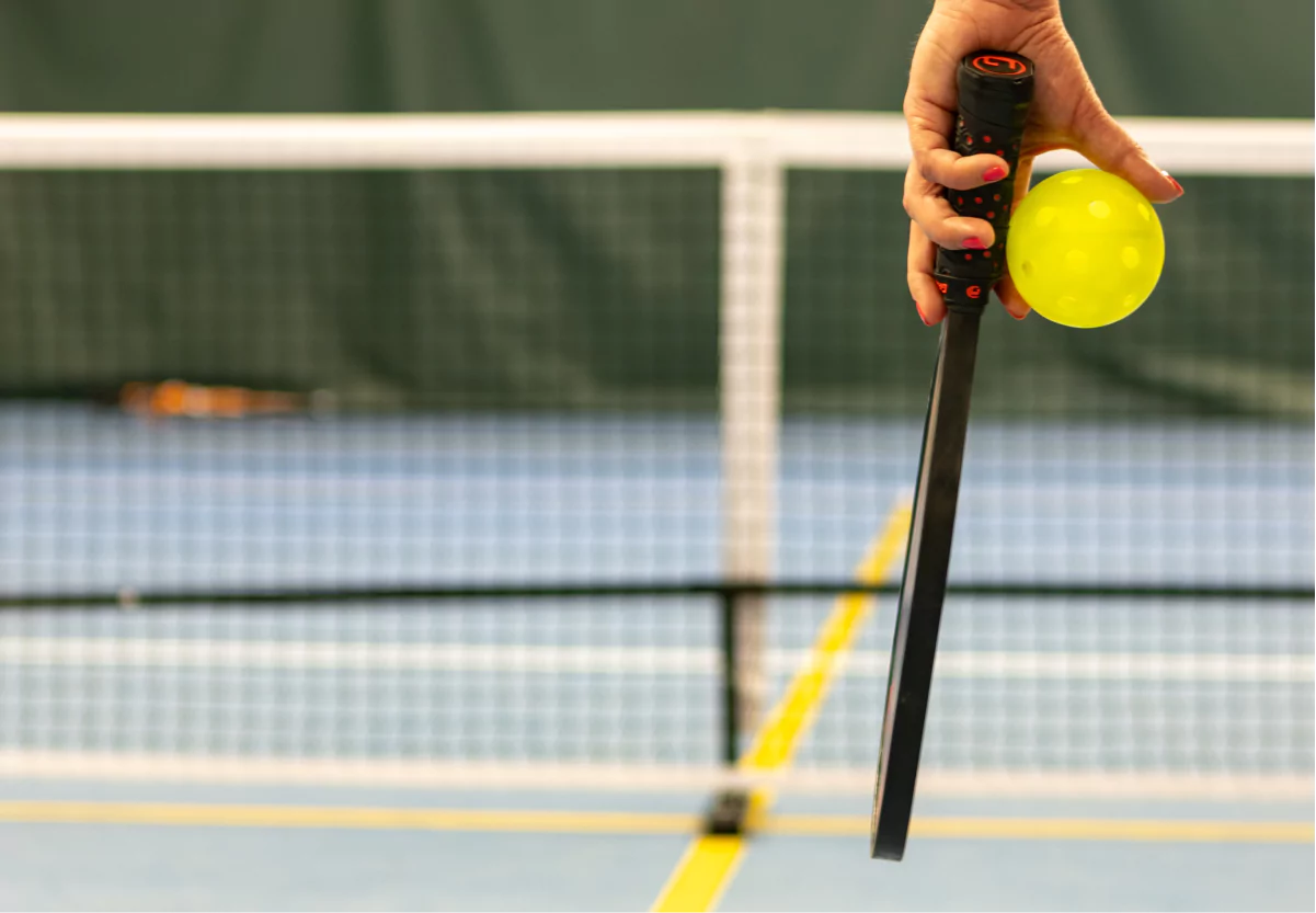 someone holding a pickleball and racket